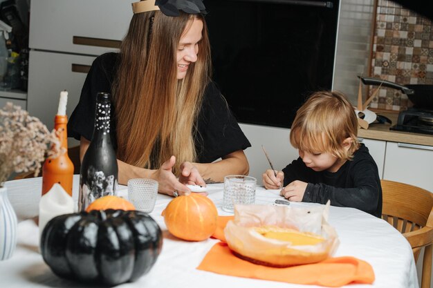 Moeder en haar zoontje zitten achter tafel en maken decoraties voor Halloween