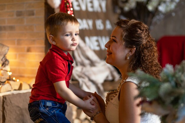 Foto moeder en jongen onder kerstboom met geschenken. vrouw met kind voor nieuwjaar