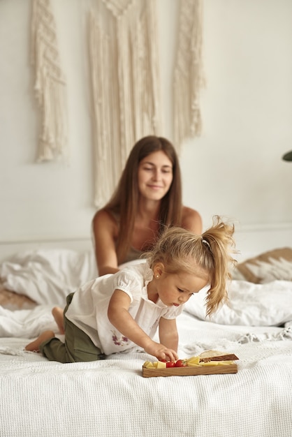 Moeder en jongste dochter proeven kaas op het bed.