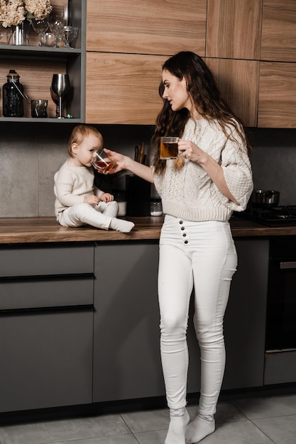 Moeder en kind dochter drinken kopje thee in de keuken Zwangerschap Mon en haar kind brengen samen tijd thuis door