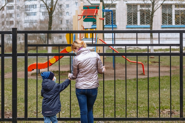 Moeder en kind in medische maskers kijken elkaar aan