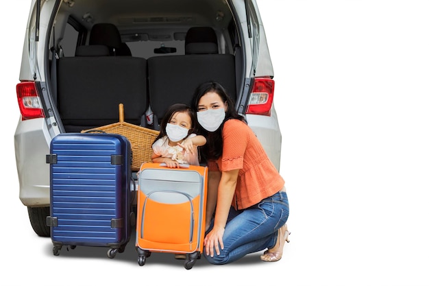 Moeder en kind klaar voor een roadtrip terwijl ze een masker dragen