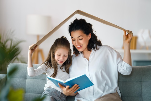 Moeder en kind meisje in de kamer met een symbool van het dak Concept van huisvesting voor jonge familie