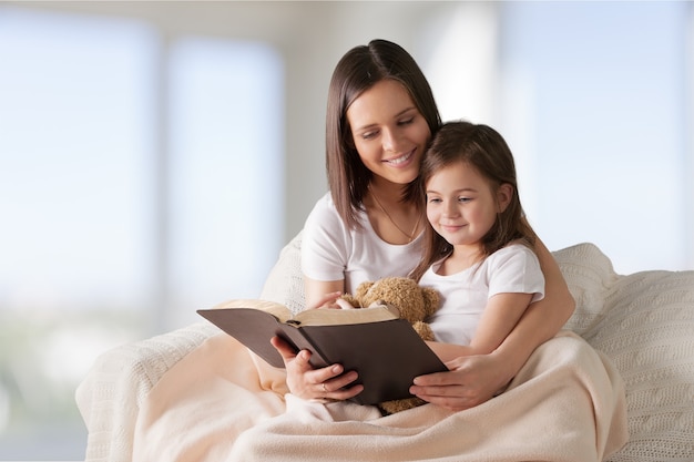 moeder en kind meisje lezen een boek in bed voordat ze gaan slapen