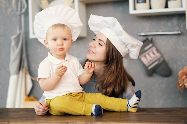 moeder en kind op keuken, witte hoeden van chef-kok, relaties van moeder en zoon