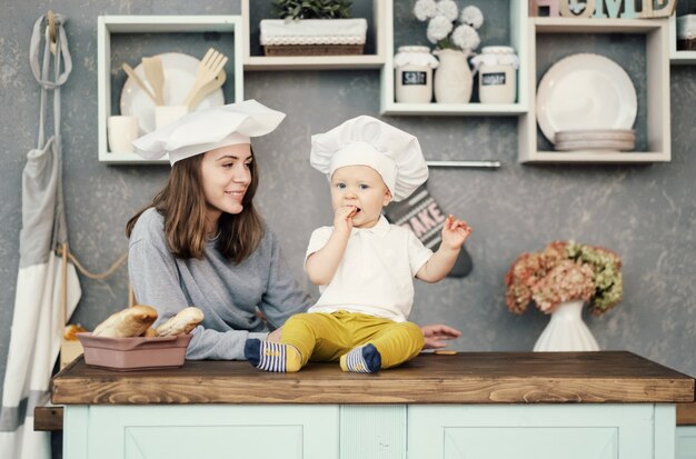 moeder en kind op keuken, witte hoeden van chef-kok