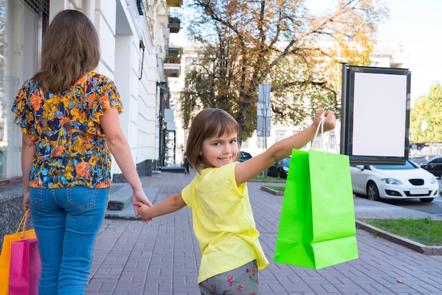 Moeder en kind op straat met boodschappentassen meisje houdt de boodschappentassen vast