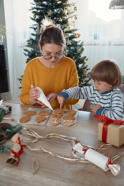 Moeder en kind samen kerstkoekjes versieren met poedersuiker