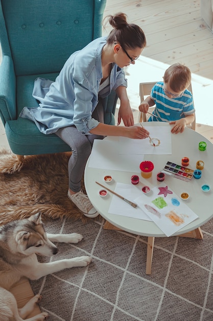 Moeder en kind schilderen samen thuis met een hond