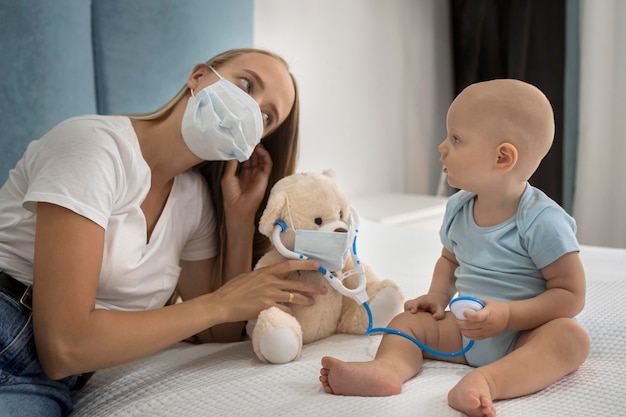 Foto moeder en kind spelen met teddy slijtage met medisch masker