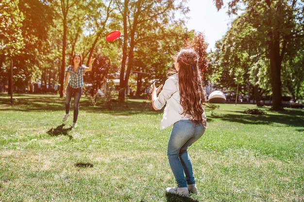 Foto moeder en kind staan voor elkaar en spelen met frisbee