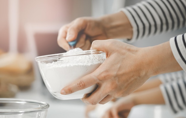 Foto moeder en kind werken samen om bloem en ingrediënt te mengen voor de kook- en bakbakkerij in de thuiskeuken