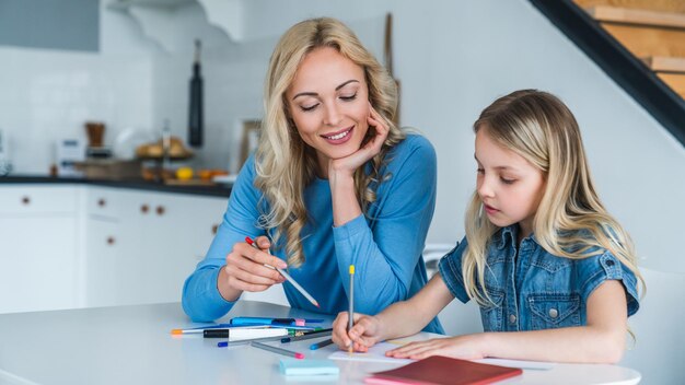 Moeder en kinddochter die thuis huiswerk maken