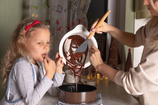 Moeder en kinddochter koken samen kerstmiscake.