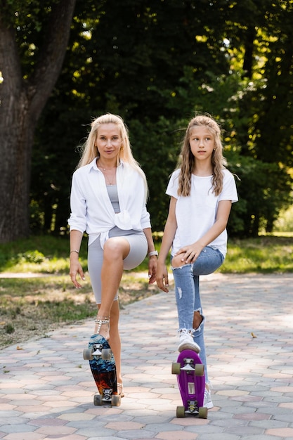 Moeder en kinddochter met skate en pennyboard in skatepark Extreme levensstijl Familie van moeder en haar kind brengen tijd samen door