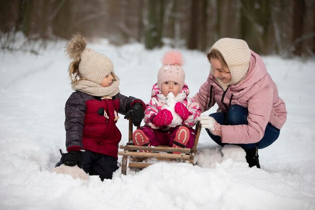 Moeder en kinderen op een vintage houten slee tegen de achtergrond van een winterbos