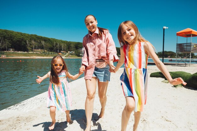 Moeder en kinderen rennen en hebben overdag plezier op het strand Vriendelijk familieconcept