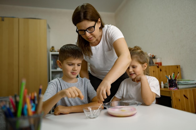 Moeder en kinderen vermaken zich thuis en experimenteren met melk en verf