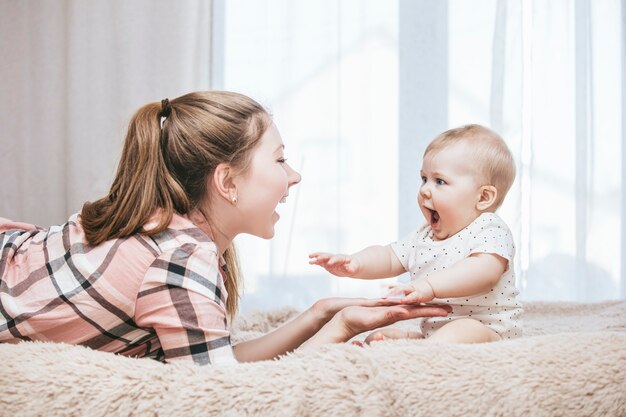 Moeder en kleine baby in bed en werden 's ochtends wakker en lachten thuis