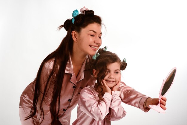 Moeder en kleine dochter in pyjama en met krullen maken op een witte achtergrond isoleren