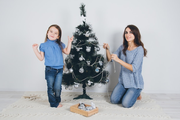 Moeder en kleine dochter versieren kerstboom