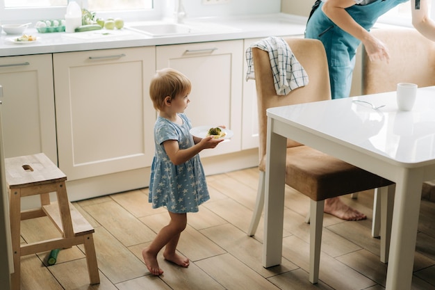 Moeder en kleine dochter zetten de tafel voor het eten thuis in de keuken.