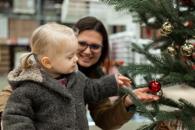 Moeder en kleine peuter dochter kiezen nieuwjaarscadeaus in de winkel klein meisje spelen met