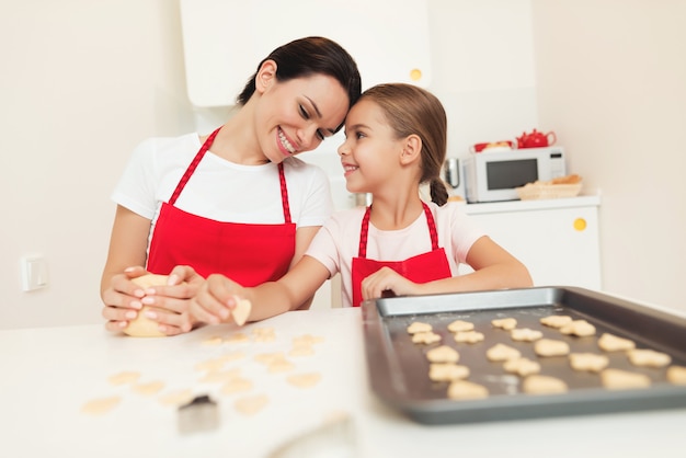 Moeder en meisje maken koekjes in de keuken.