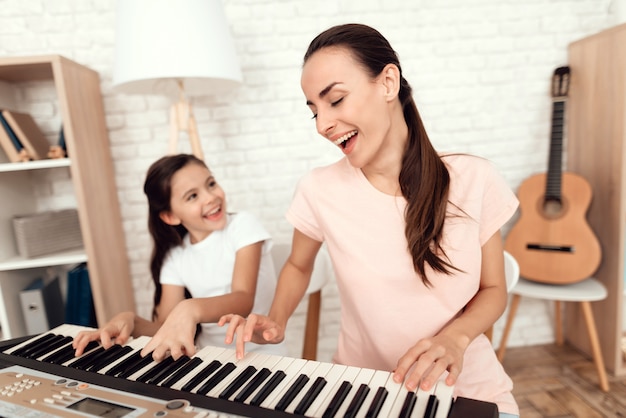 Moeder en meisje spelen de synthesizer thuis