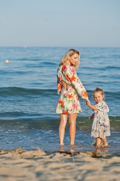 Moeder en mooie dochter die plezier hebben op het strand Portret van een gelukkige vrouw met een schattig klein meisje op vakantie