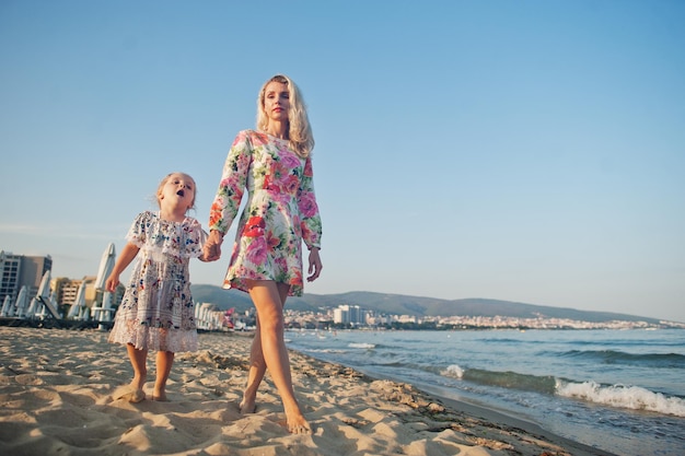 Moeder en mooie dochter die plezier hebben op het strand Portret van een gelukkige vrouw met een schattig klein meisje op vakantie