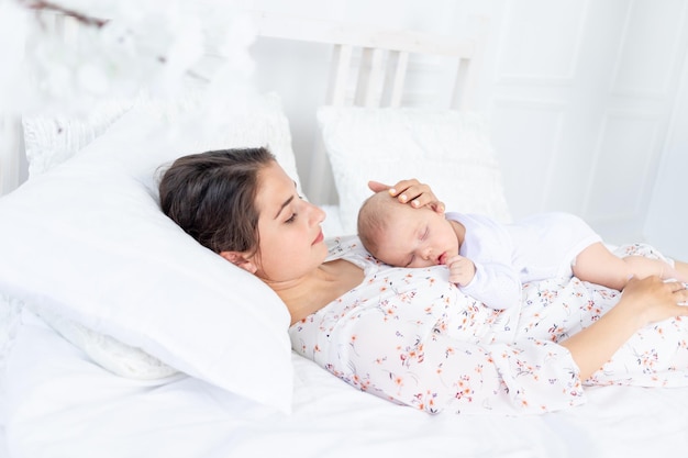 Moeder en pasgeboren baby slapen samen, moeder legt baby te slapen op het bed in de slaapkamer, het concept van moederschap en gezonde slaap
