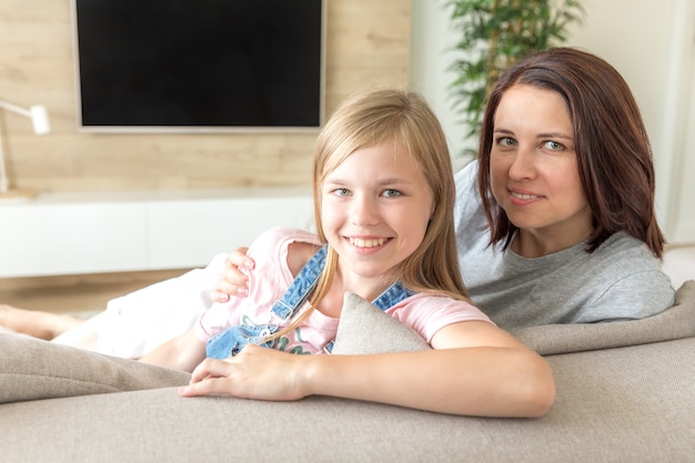 Moeder en pre-tienerdochterzitting op laag die, Gelukkig familieconcept glimlachen