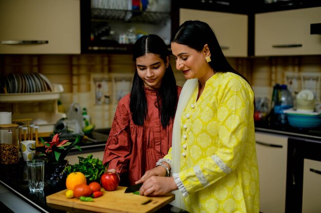 moeder en schattige dochter snijden groene chili in de keuken Indisch Pakistaans model