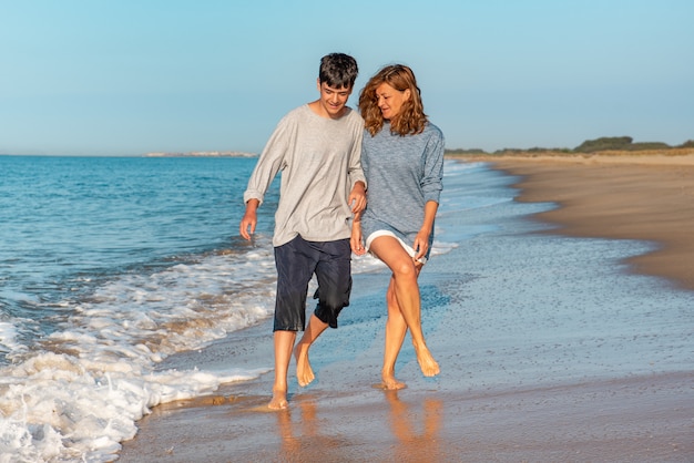 Moeder en tiener plezier met de golven op het strand