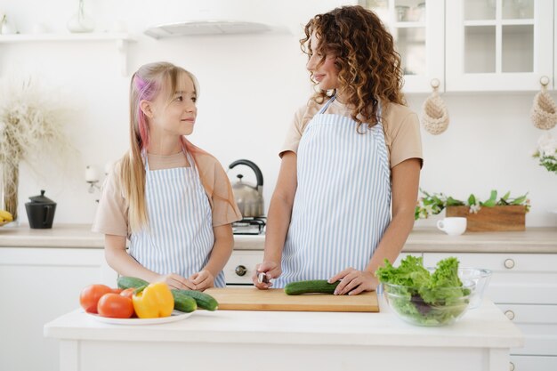 Moeder en tienerdochter die groentesalade voorbereiden bij keuken