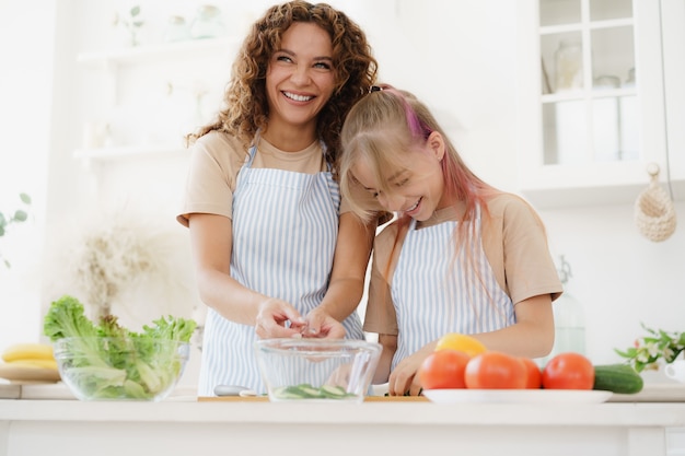 Moeder en tienerdochter die groentesalade voorbereiden bij keuken