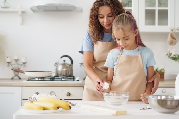 Moeder en tienerdochter maken samen deeg voor gebak in de keuken