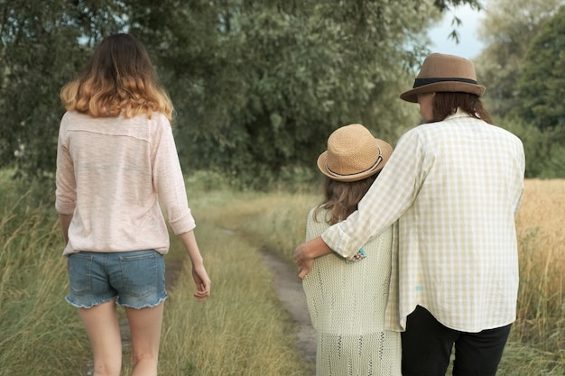 Moeder en twee dochters die samen langs landweg lopen, achtermening