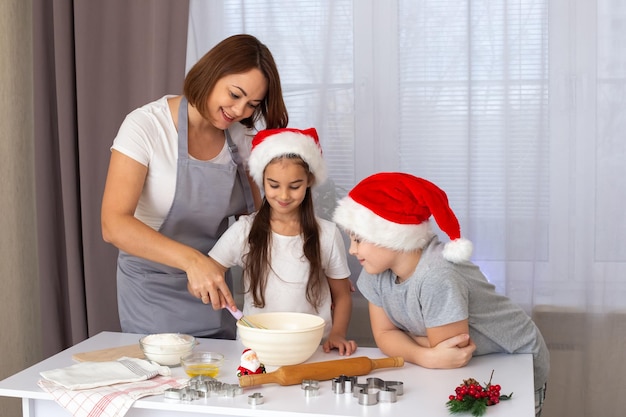 Moeder en twee kinderen in rode hoofdletters die kerstkoekjes koken in de keuken