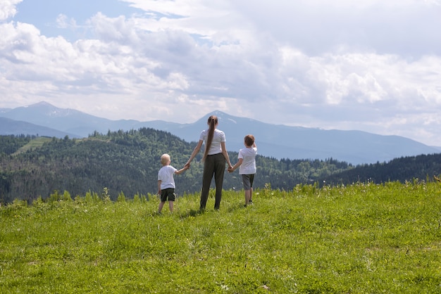 Moeder en twee kleine zonen staan hand in hand op een groen veld