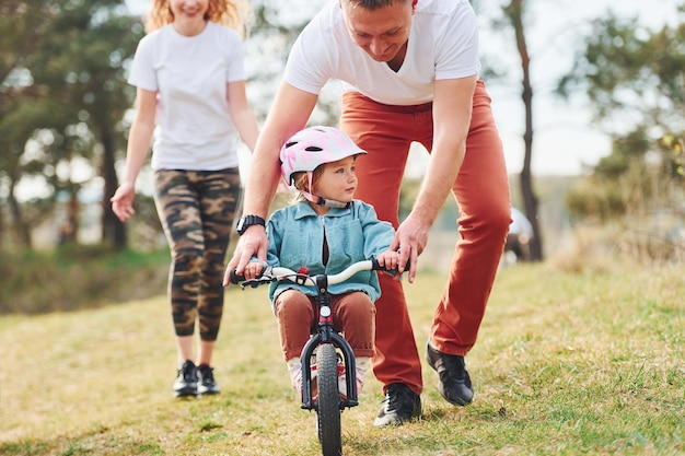 Moeder en vader leren dochter buiten fietsen