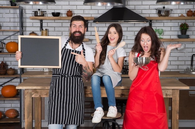 Moeder en vader leren dochter koken klein meisje met mama en papa in de keuken doen alles samen koken volgens recept vaderdag familieleden hebben plezier tijdens het koken