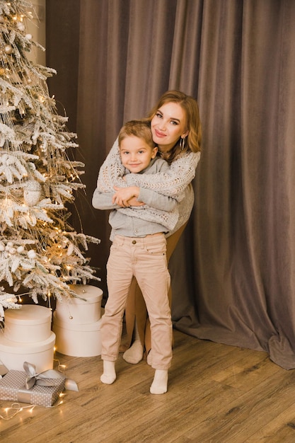 Moeder en zoon bij de kerstboom thuis