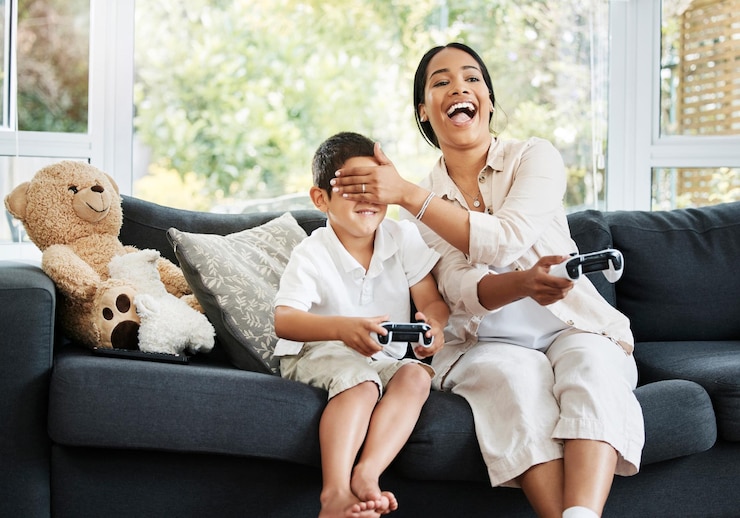 Foto moeder en zoon die videogames spelen, plezier hebben en samen genieten van quality time vrolijke binding en zorgeloos kind en ouder met behulp van een gameconsole of interactieve moderne technologie