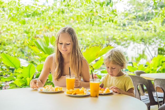 Moeder en zoon eten fruit en sap in een café