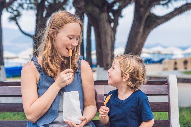 Moeder en zoon eten gebakken zoete aardappelen in het park