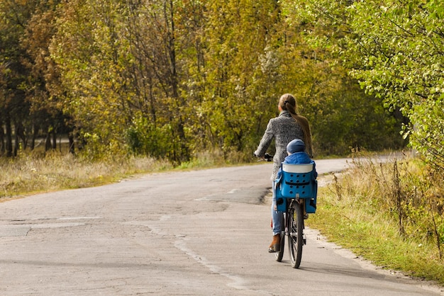 Moeder en zoon fietsen op de herfstweg Achteraanzicht