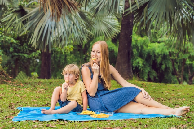 Moeder en zoon hadden een picknick in het park. Eet gezond fruit - mango, ananas en meloen. Kinderen eten gezond voedsel.