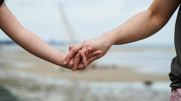 Moeder en zoon hand in hand bij de zee natuur achtergrond